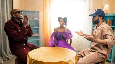 A still from the video for “Ma Cherie (Remix)” showing Bien and Fally Ipupa sitting on a table with a woman in between them.