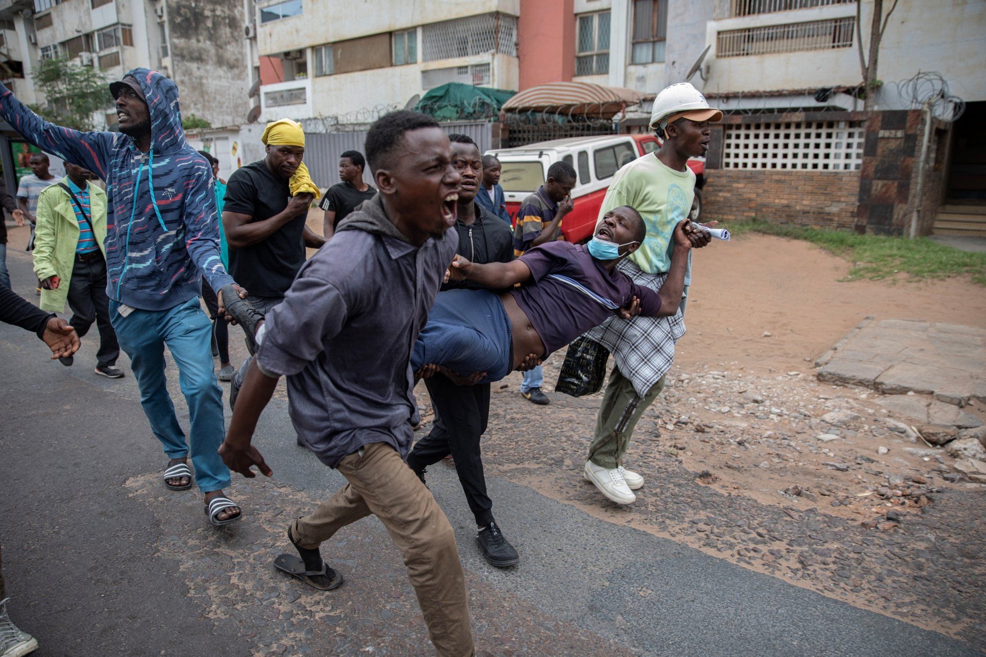 Young protesters demonstrating on a street in Mozambique, with one man shouting while others move energetically