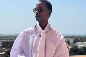  Senegalese filmmaker Moe Sow posing for a picture in a white tunic-like outfit with a skyline behind him.